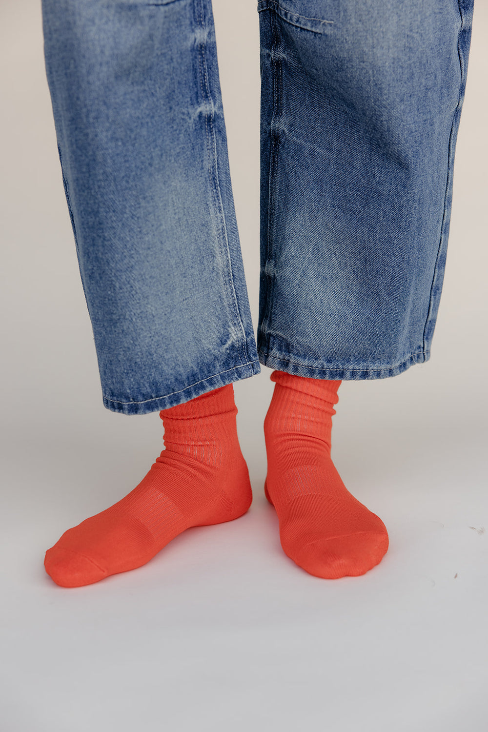 Person wearing bright red socks and blue jeans on a white background