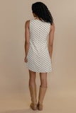 Woman wearing a polka dot dress with beige boots on a beige background