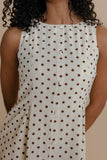 Close-up of a sleeveless polka dot dress with a beige background