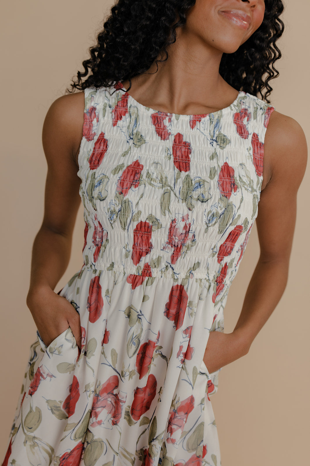 Woman wearing a floral dress with red flowers on a beige background