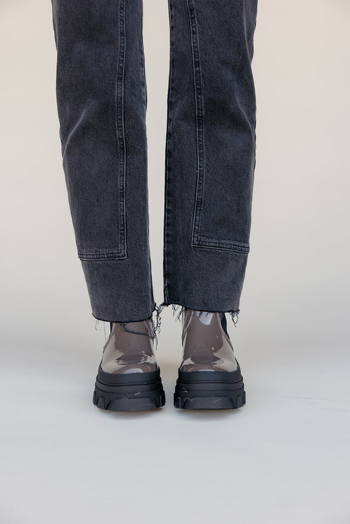 Person wearing black jeans and transparent shoes on a white background