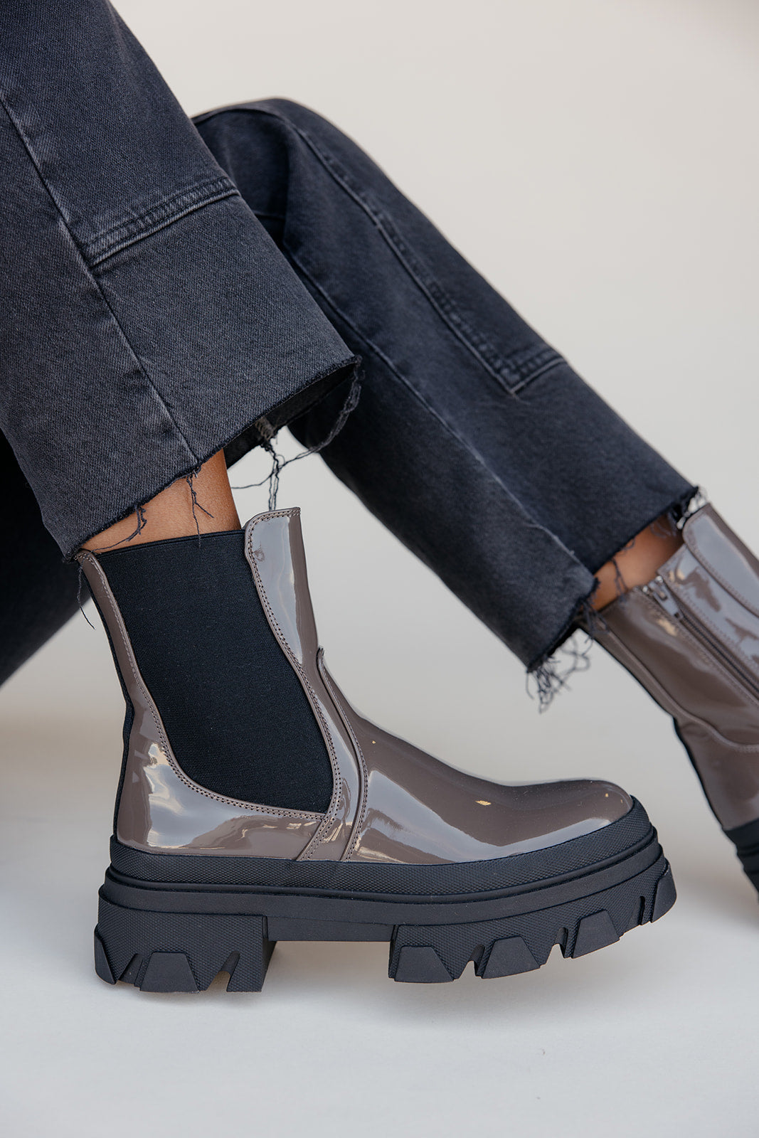 Person wearing transparent rain boots with black soles on a light background