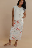Woman wearing a sleeveless button-up top and patterned skirt on a beige background