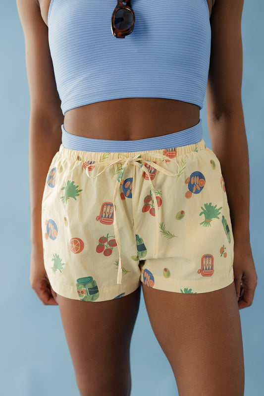 Person wearing a blue crop top and patterned shorts against a blue background