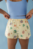 Person wearing a blue tank top and patterned shorts against a light blue background
