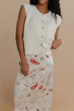 Woman wearing a textured sleeveless top and patterned skirt against a beige background