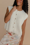Woman wearing a white knitted sleeveless top against a beige background