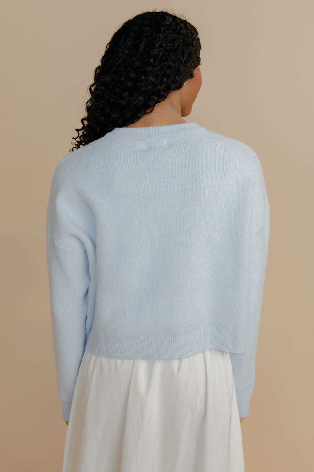 Person wearing a light blue sweater against a beige background