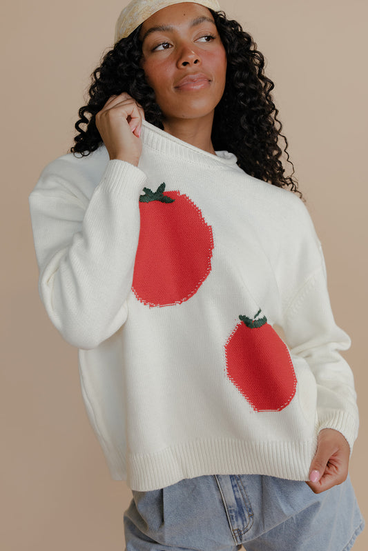 Woman wearing a cream sweater with red tomato designs on a beige background