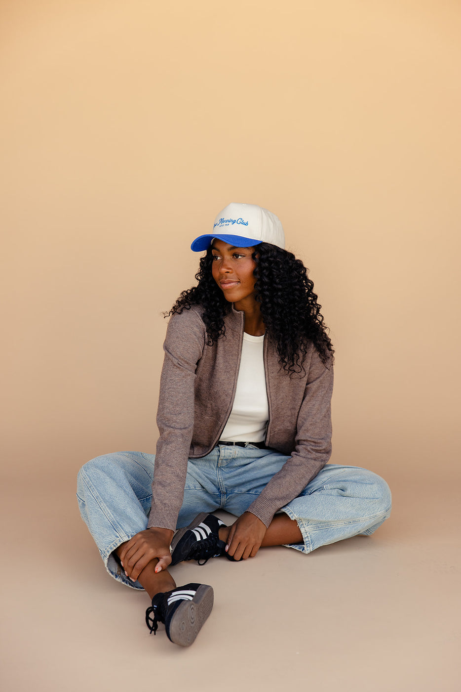 a woman sitting cross legged with a hat