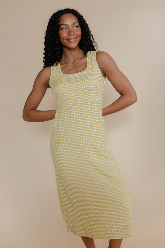 Woman wearing a yellow checkered dress against a beige background