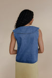 Woman wearing a blue denim top against a beige background