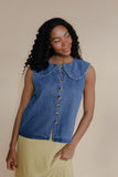 Woman wearing a denim sleeveless top with a beige background