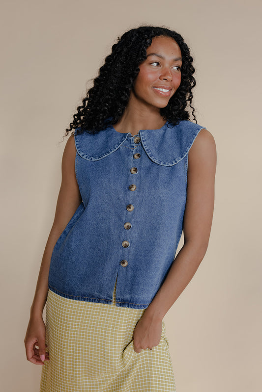 Woman wearing a denim sleeveless shirt with a beige background