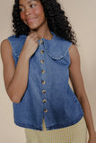 Woman wearing a blue denim vest against a beige background