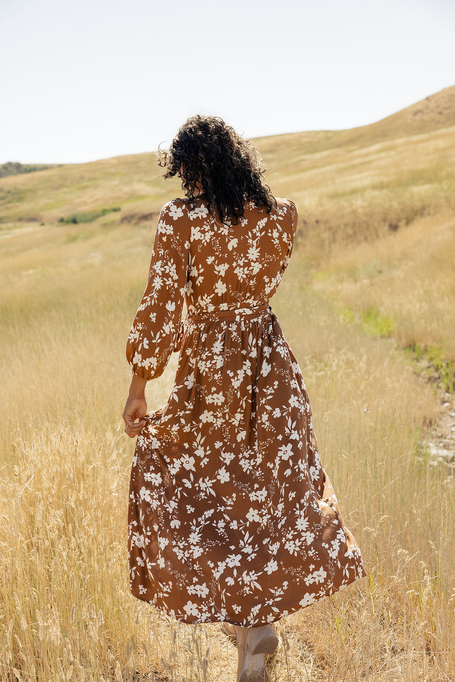 a woman in a long dress walking in a field