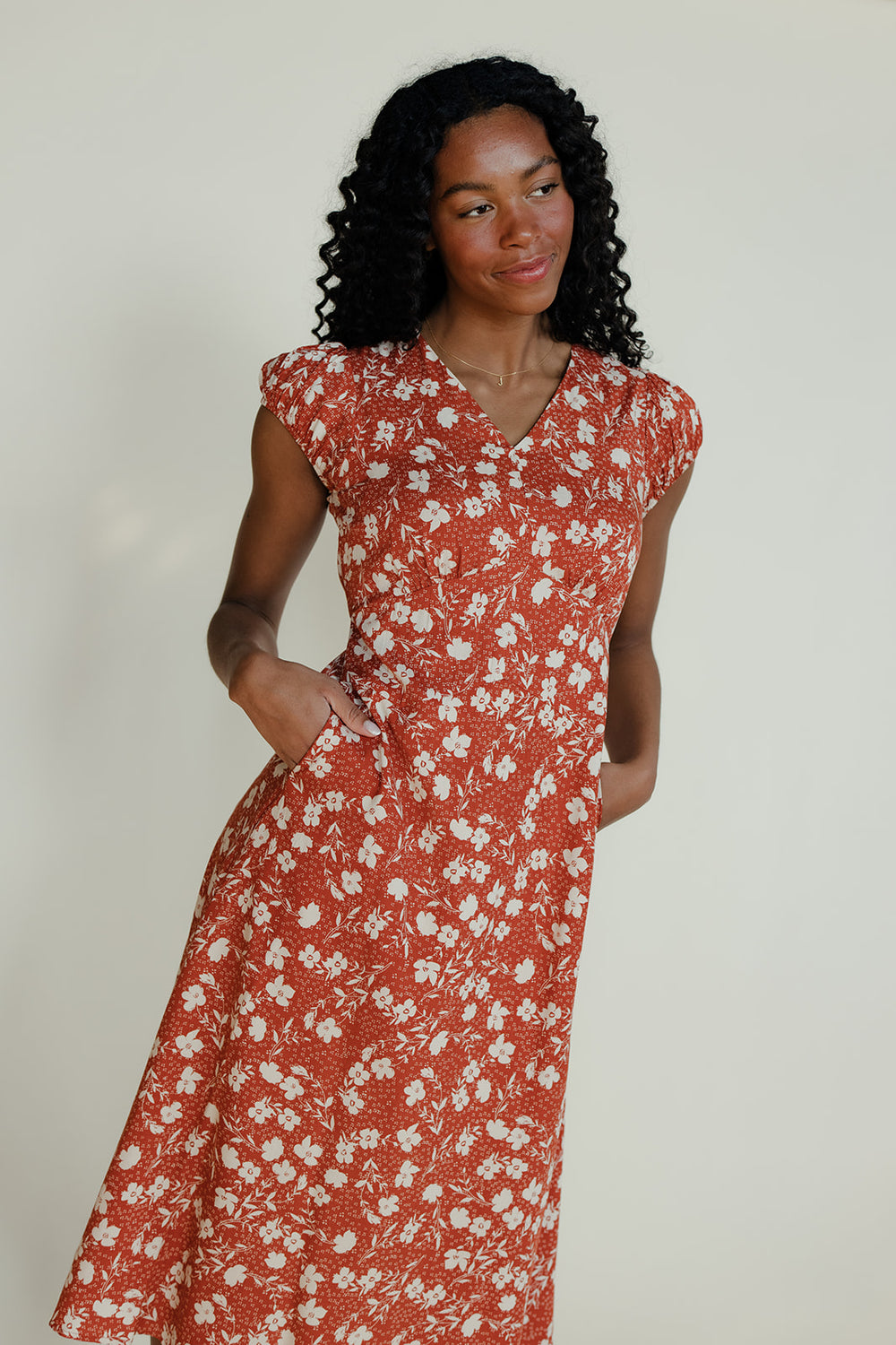 Woman wearing a red floral dress against a plain background