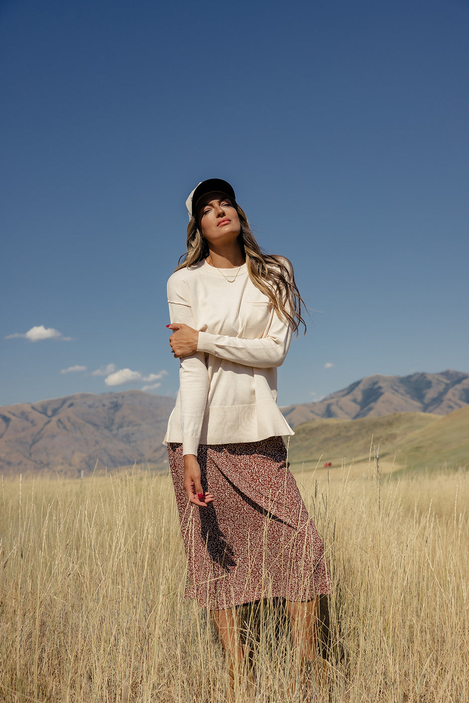 a woman in a field with mountains in the background