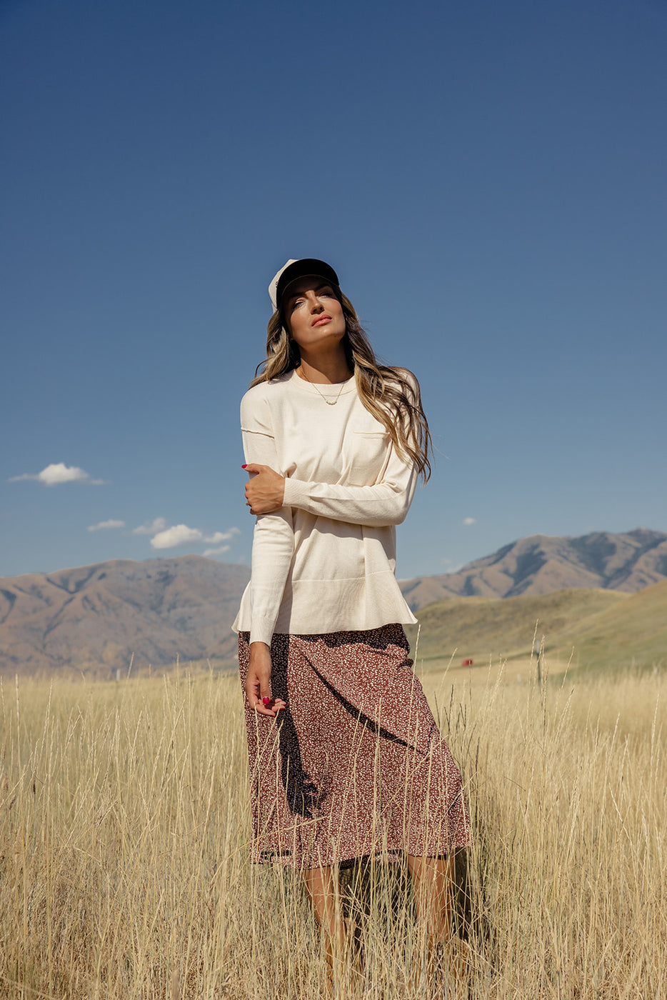 a woman in a field with mountains in the background