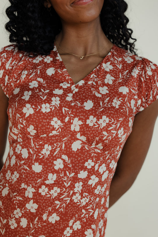 Woman wearing a red floral dress against a white background
