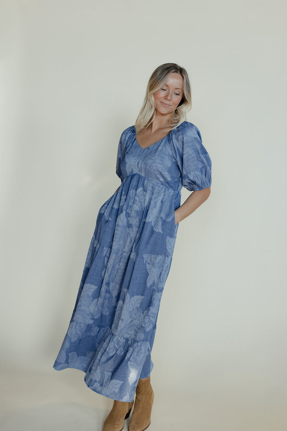 Woman wearing a blue floral dress against a plain background