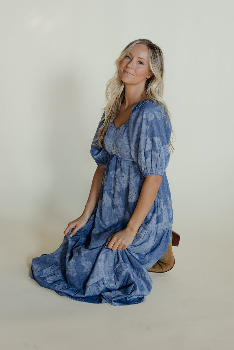 Woman wearing a blue dress sitting on a white background