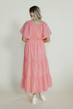 Woman wearing a pink dress against a plain background