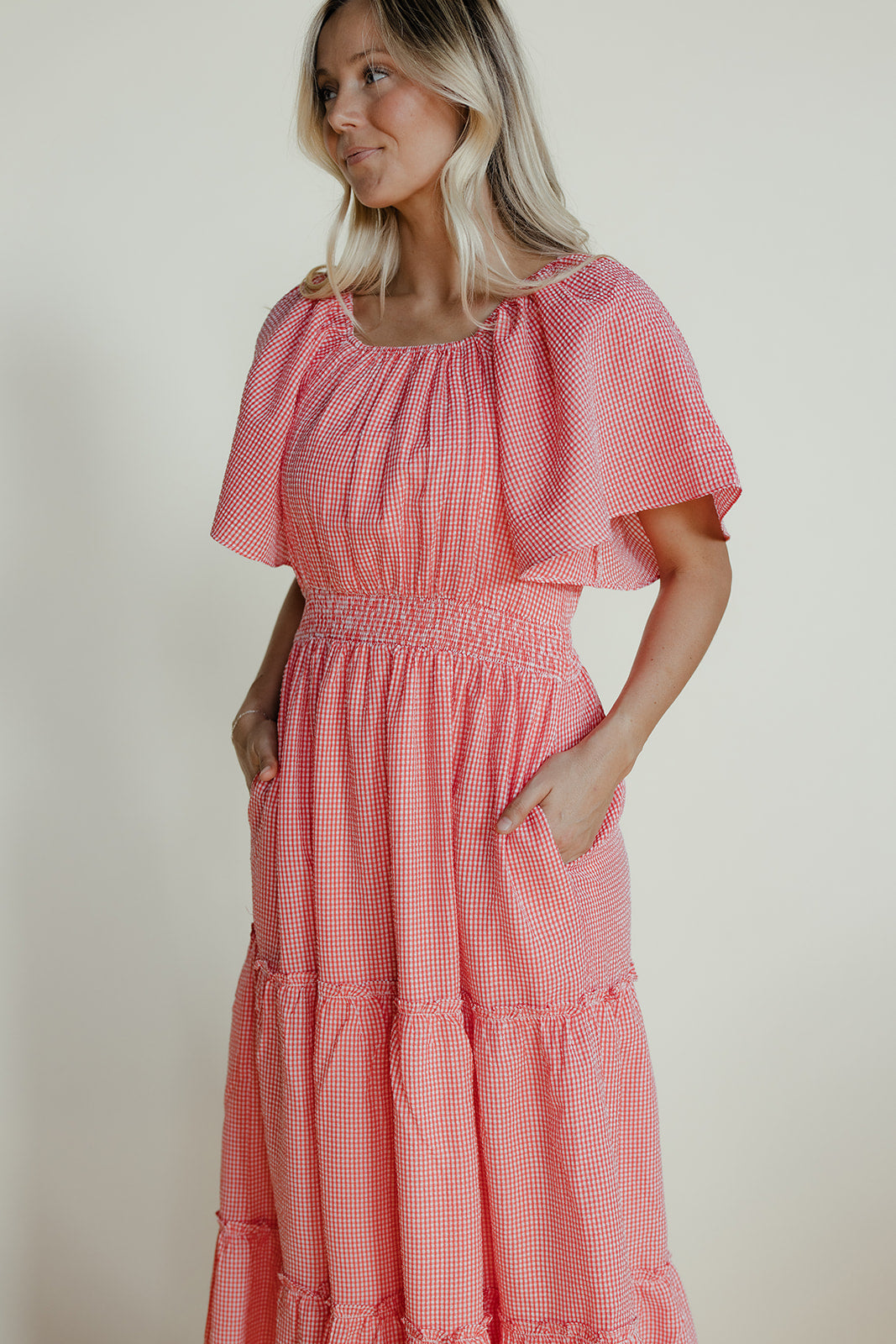 Woman wearing a pink checkered dress against a plain background