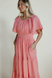 Woman wearing a pink checkered dress against a plain background