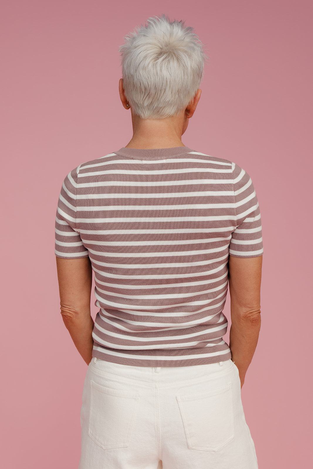 Woman wearing a striped tee shirt against a pink background