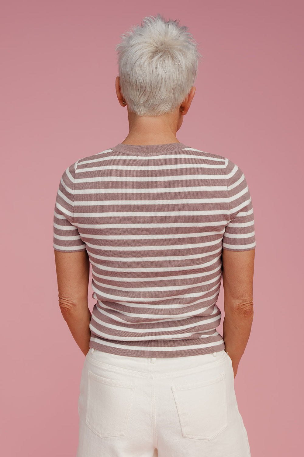 Woman wearing a striped tee shirt against a pink background