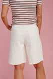 Person wearing white shorts and a striped shirt on a pink background