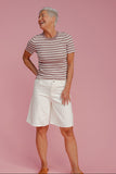 Woman wearing a striped shirt and white shorts on a pink background