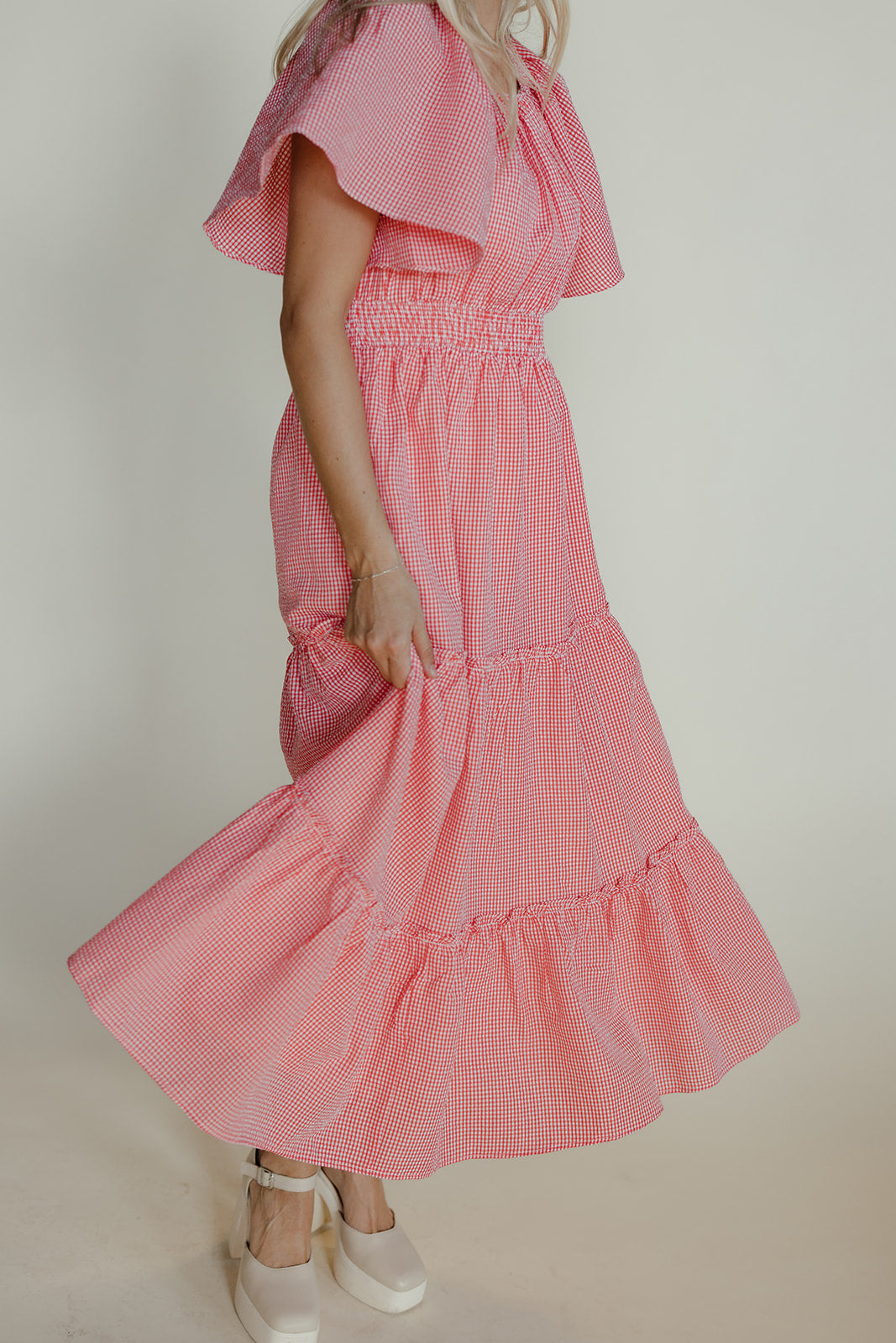 Woman wearing a pink checkered dress against a plain background