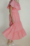 Woman wearing a pink checkered dress against a plain background