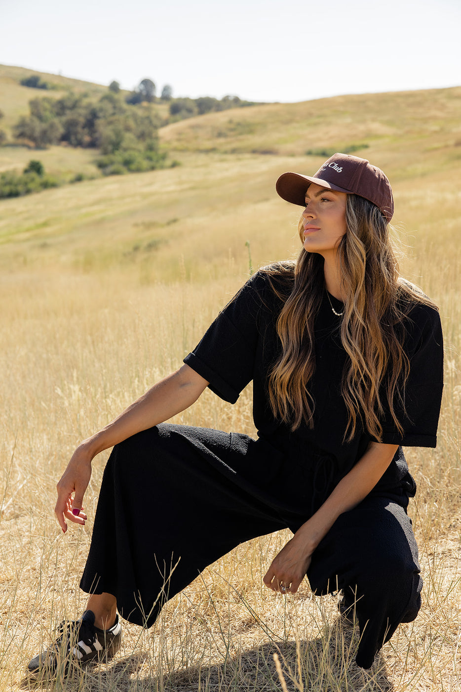 a woman in a hat sitting in a field