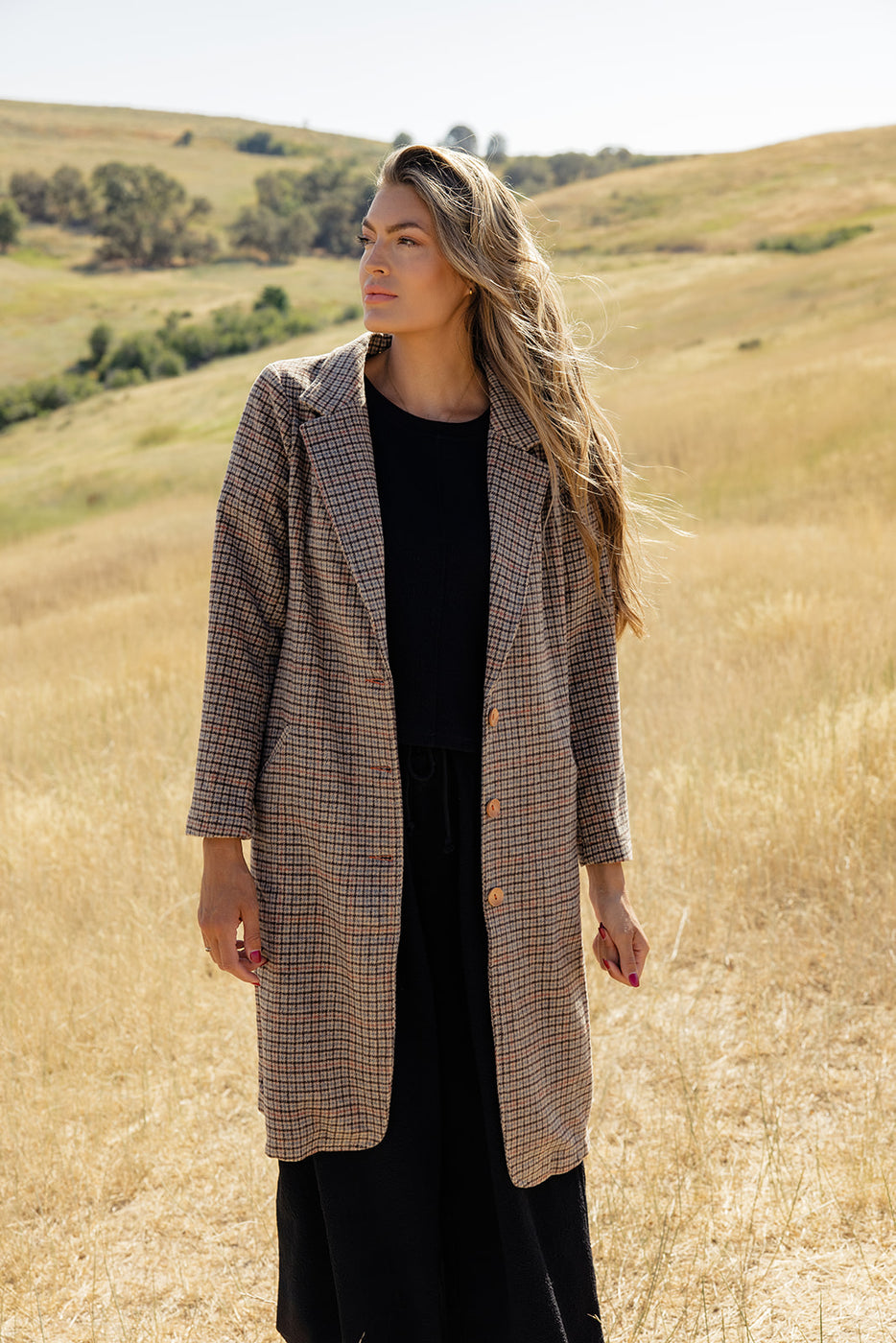 a woman in a long coat in a field