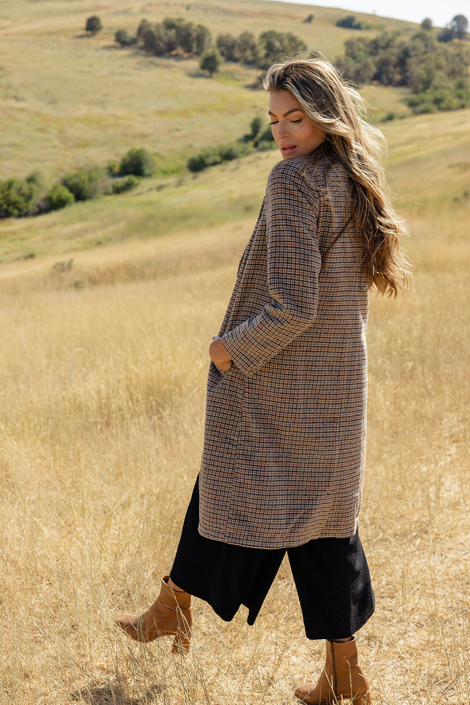 a woman in a long coat in a field