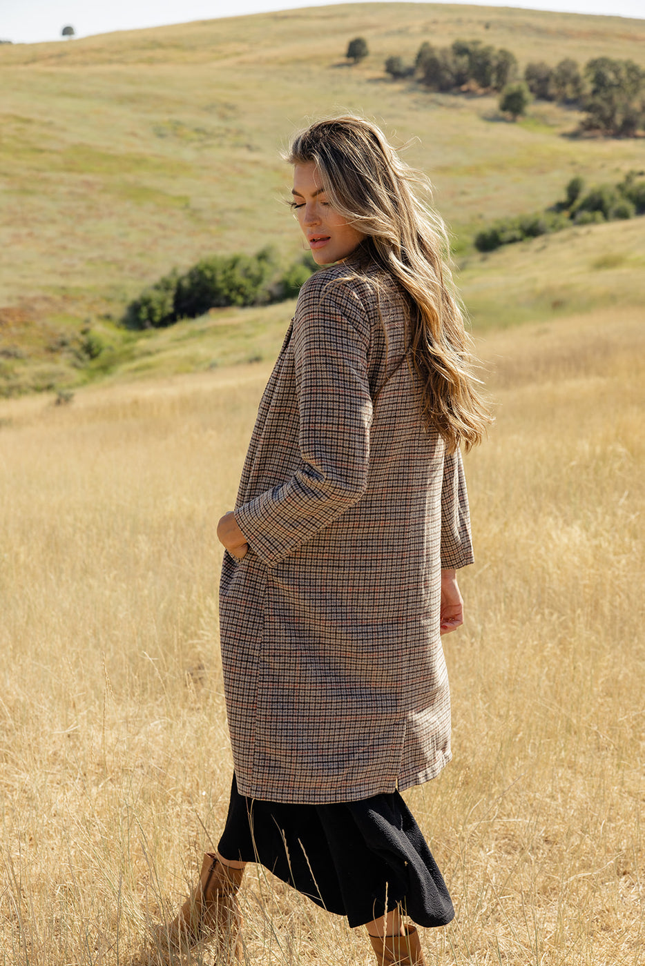 a woman in a brown coat in a field