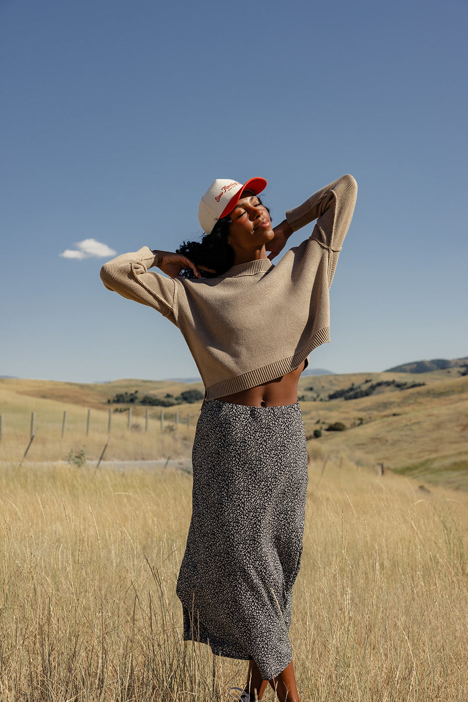 a woman in a field with her hands behind her head