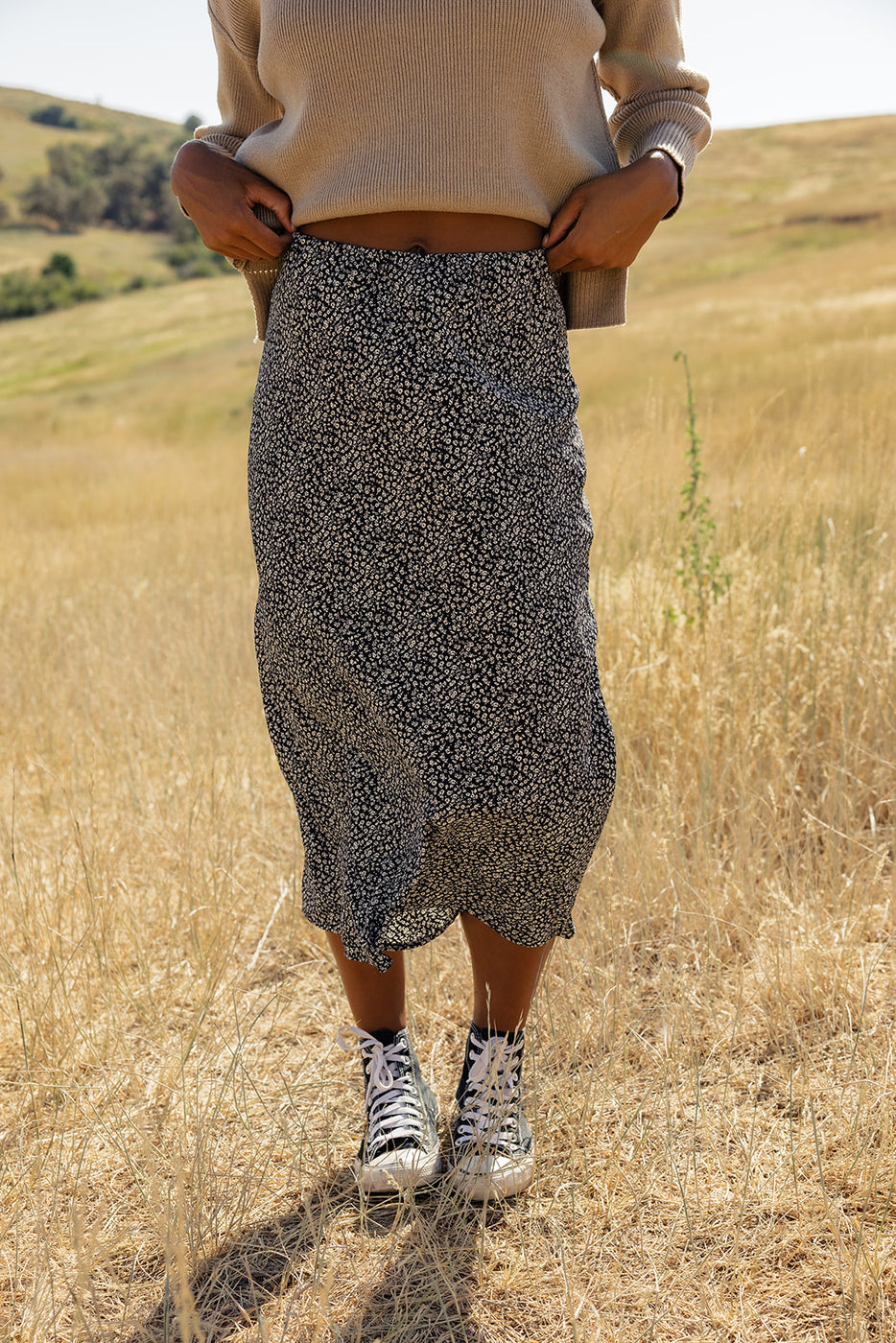 a woman wearing a skirt and sneakers