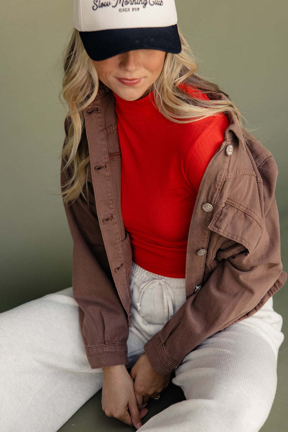 a woman in a red turtleneck and brown jacket