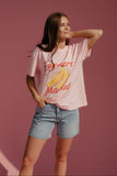 Woman wearing a pink t-shirt with 'Farmers Market' and banana graphic on a pink background