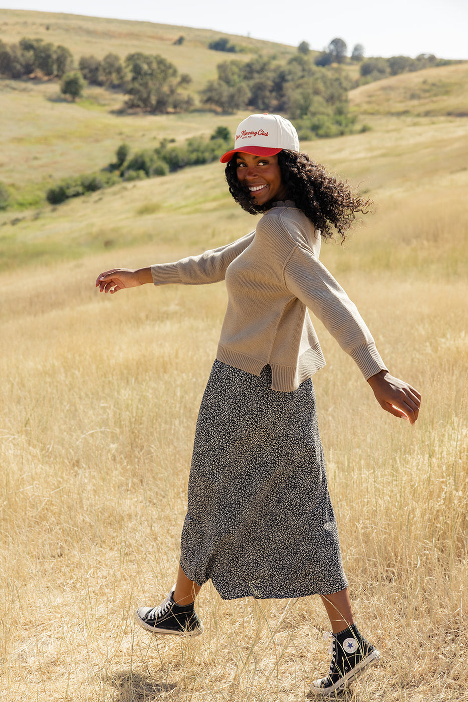 a woman in a long skirt and a hat in a field