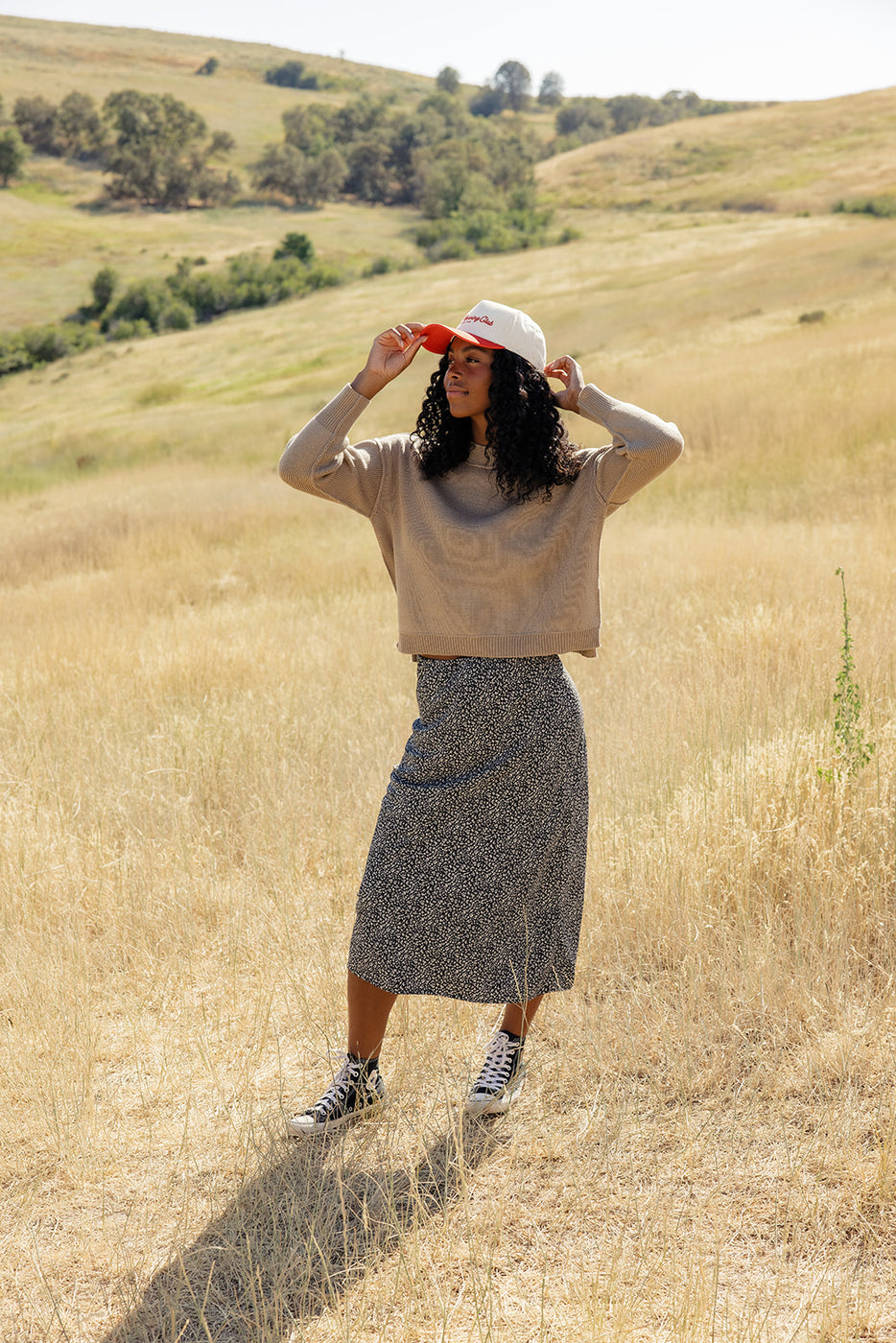 a woman in a long skirt and a hat in a field