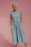 Woman wearing a light blue dress against a pink background