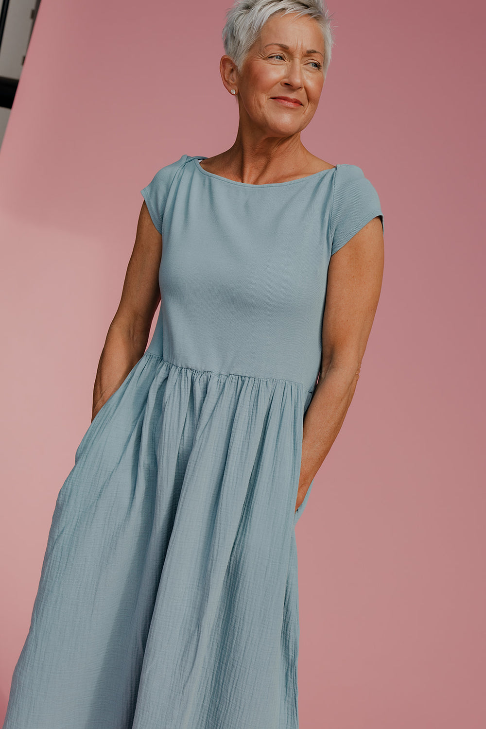 Woman wearing a light blue dress against a pink background