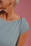 Close-up of a person wearing a light blue top against a pink background