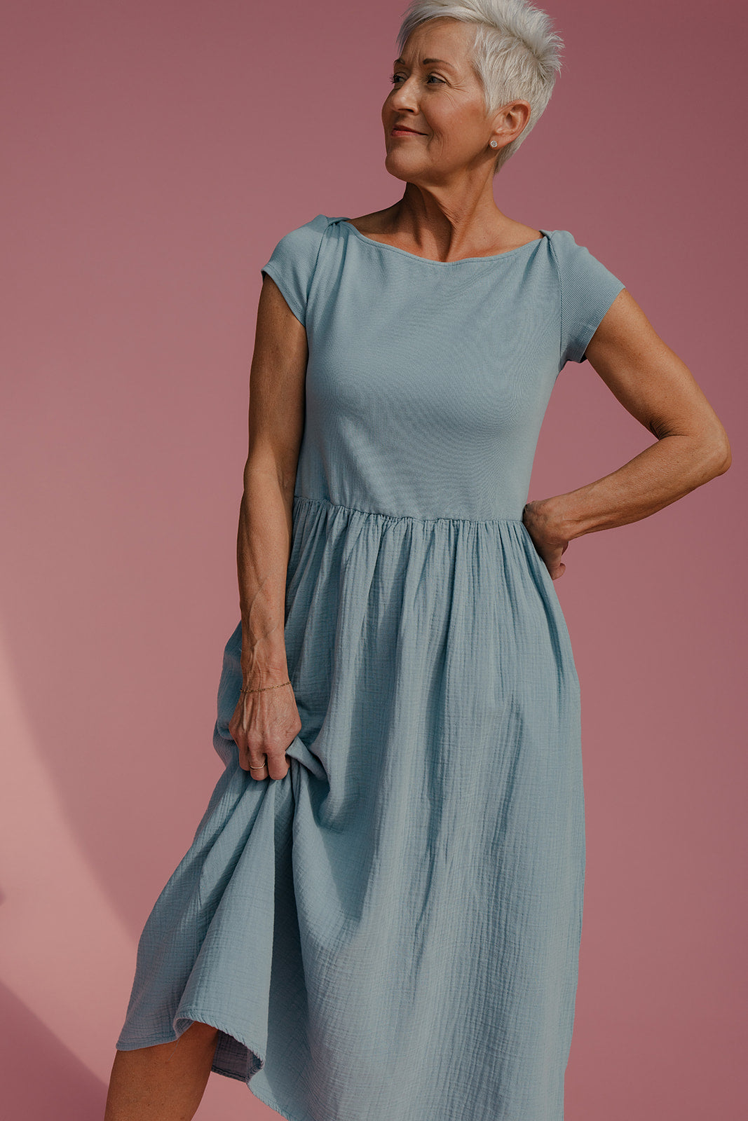 Woman wearing a blue dress against a pink background