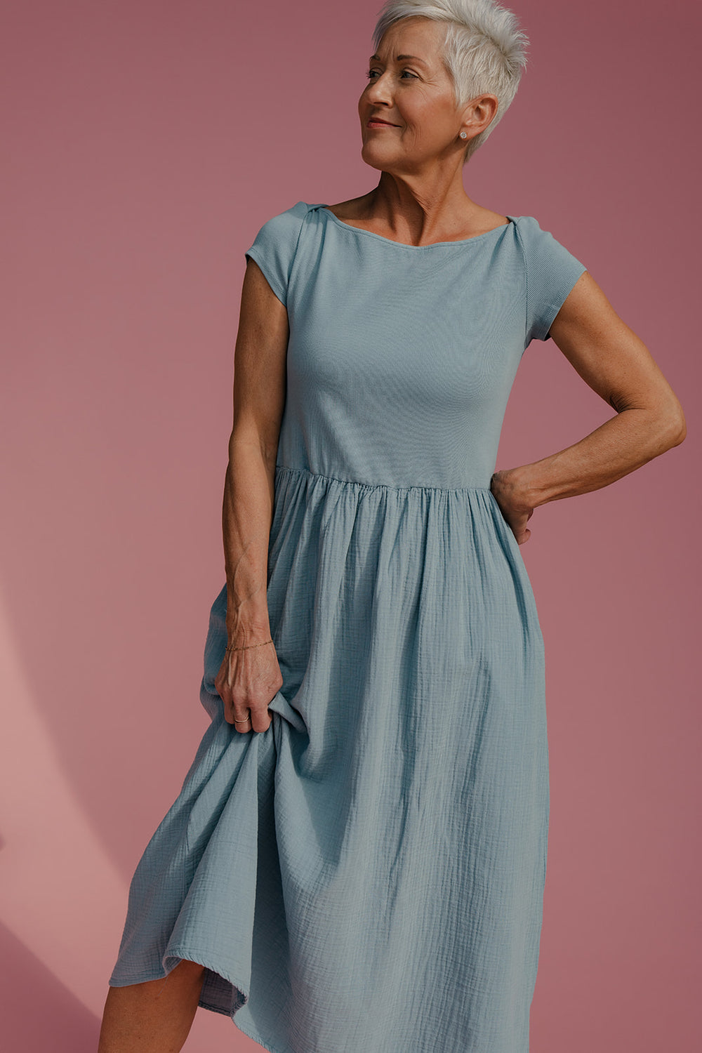 Woman wearing a blue dress against a pink background